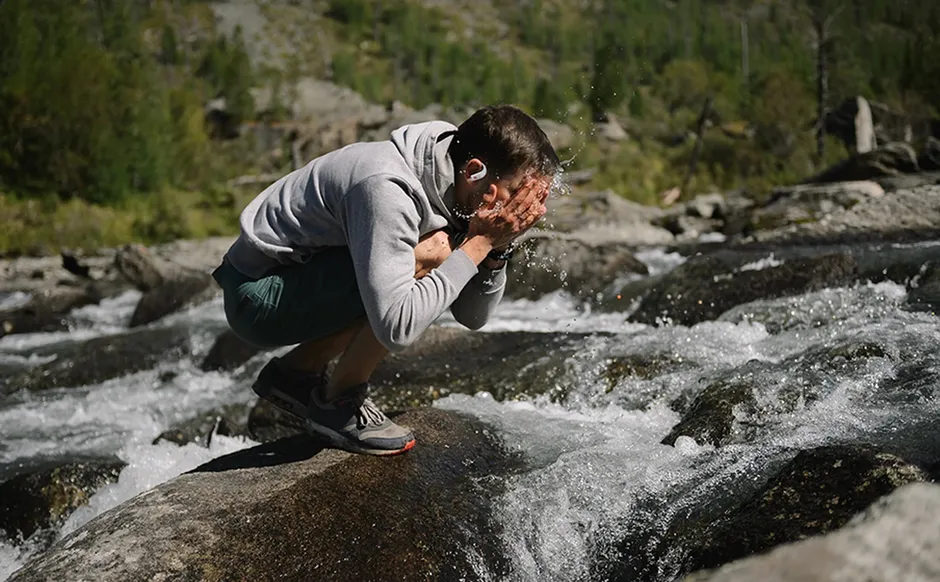 Uomo si rinfresca al fiume indossando JBL Endurance Peak 4